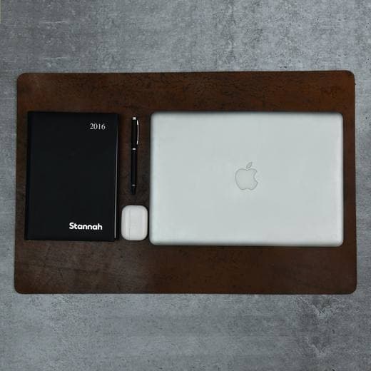 A leather desk mat with a laptop, notebook and pen
